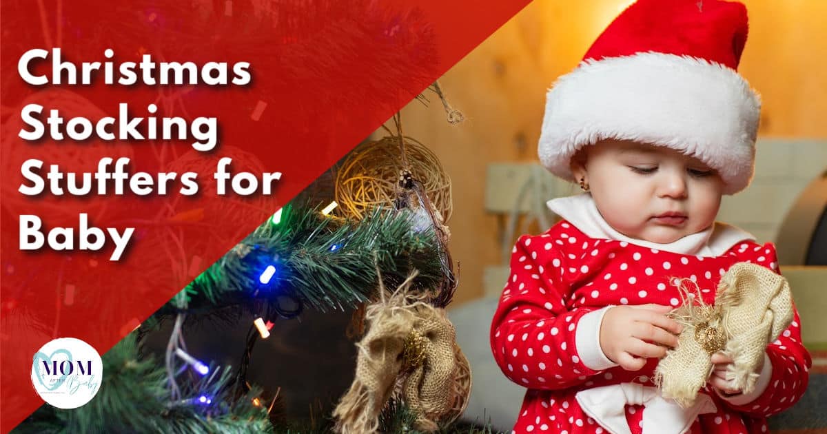 Photo of baby sitting next to Christmas tree in a santa hat holding a small item