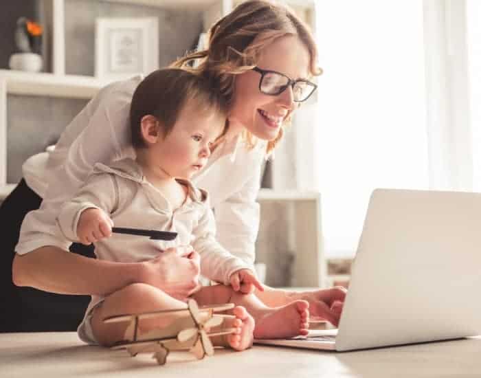 mother sitting with child, both, looking at a laptop together