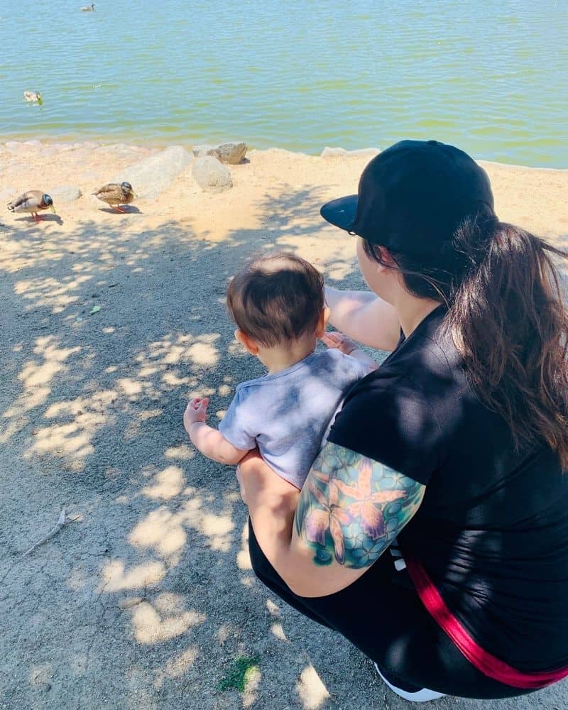 image of woman with child kneeling on the sand at a lake