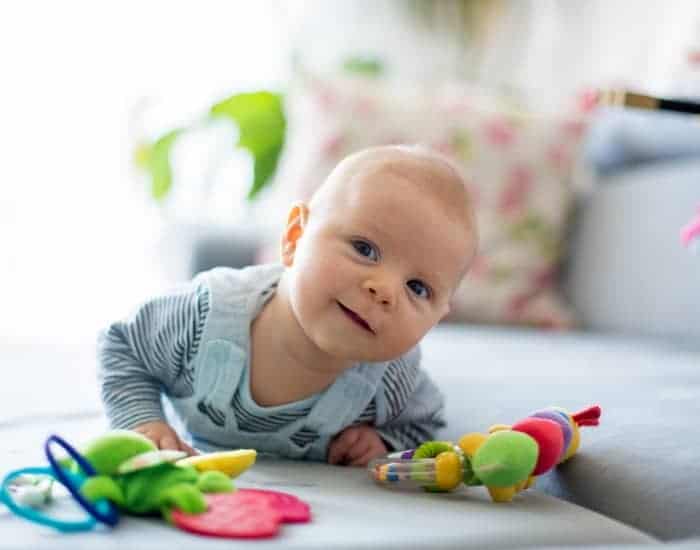 baby laying on tummy playing with colorful baby toys.