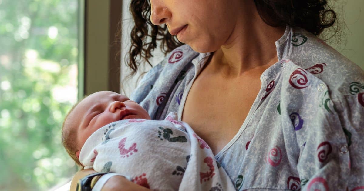 image of a woman holding a newborn baby with her head angled down towards the baby