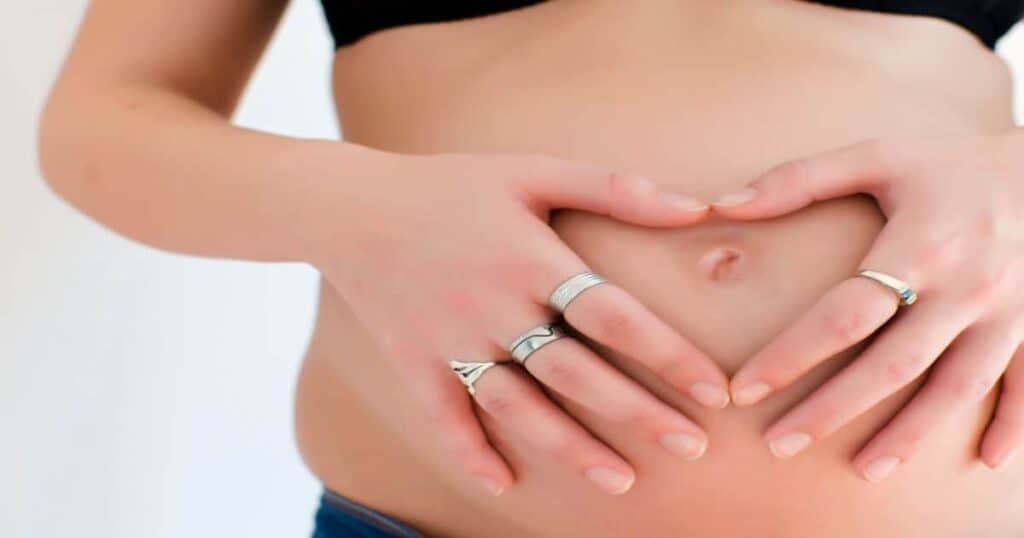 Pregnant woman holding her hands over her belly in the shape of a heart