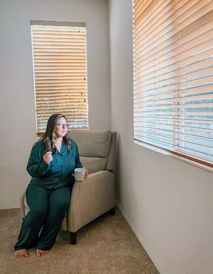 stay at home mom blog —image of karssa in dark green kindred bravely pajamas looking out the window and drinking coffee