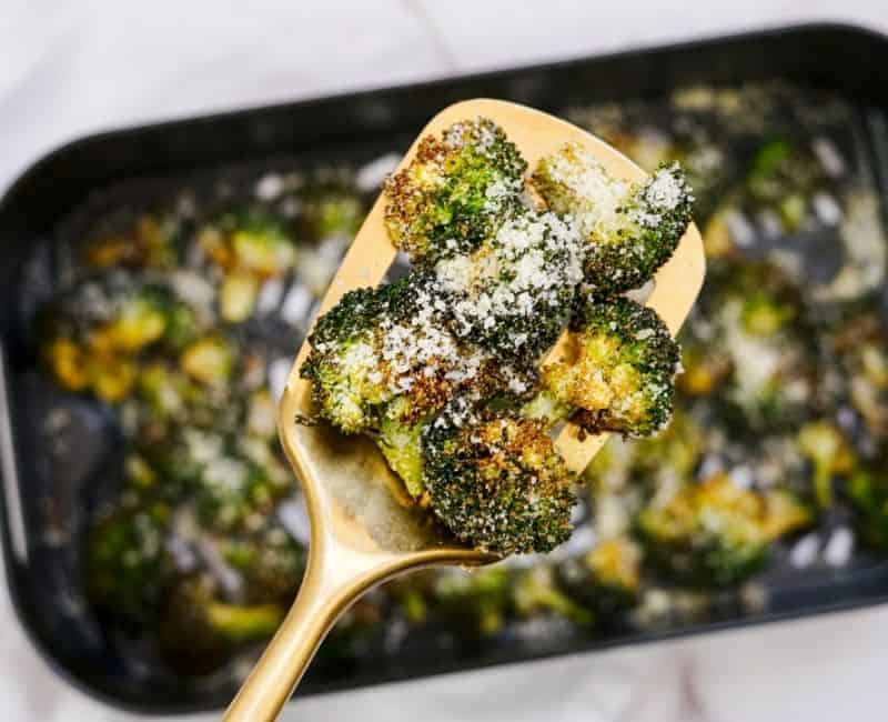 close up of the air fryer garlic parmesan broccoli being held on the gold spatula