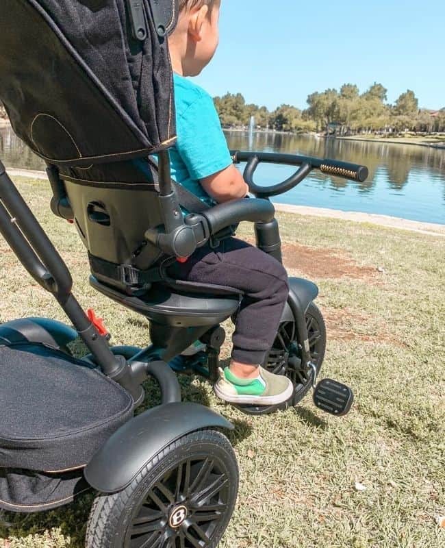 forward facing shot of my son sitting in his bentley trike overlooking the lake on the grass