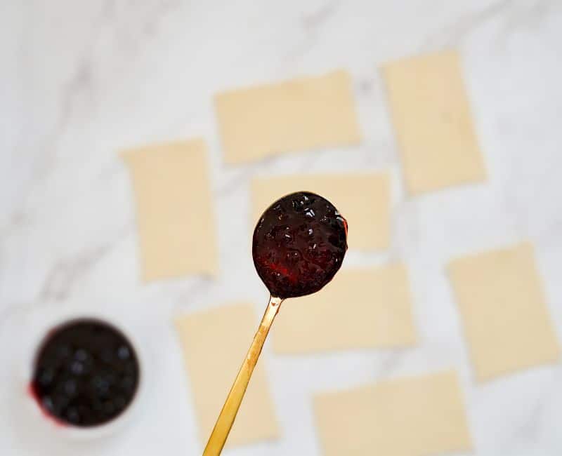 close up shot of jelly on a spoon with rectangular pie crusts in the background