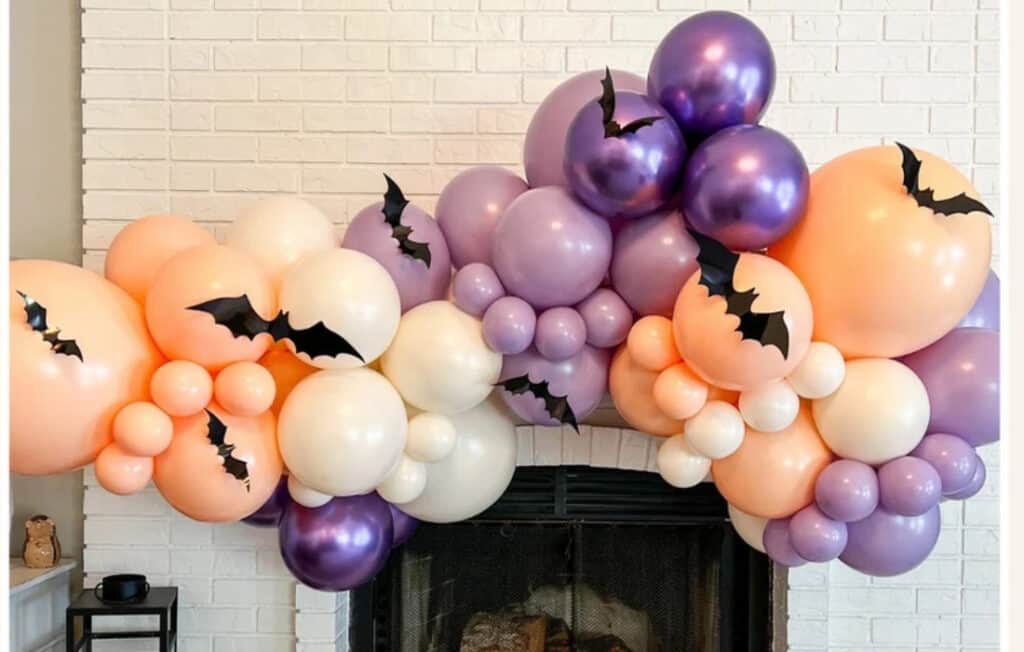 Close up image of a pastel purple and orange halloween balloon garland on Etsy