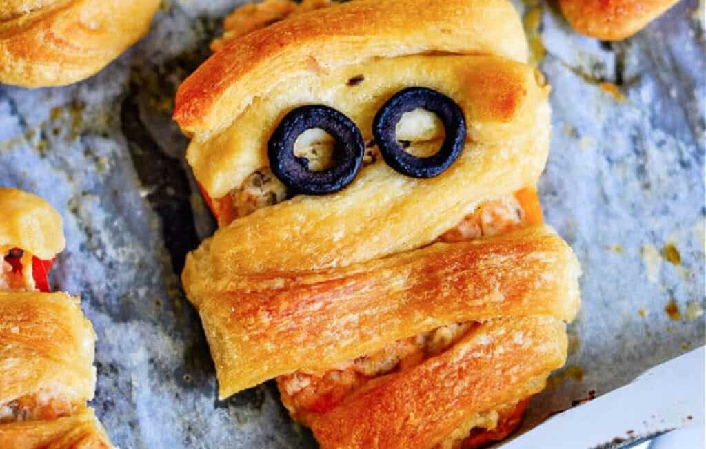 Close up photo of a stuffed sweet pepper wrapped in a croissant to look like a mummy pepper for halloween