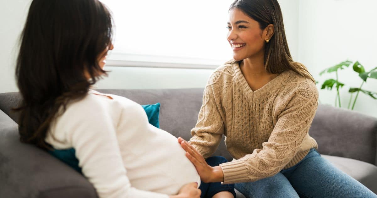 image of a pregnant woman sitting on a couch next to either a doula or midwife