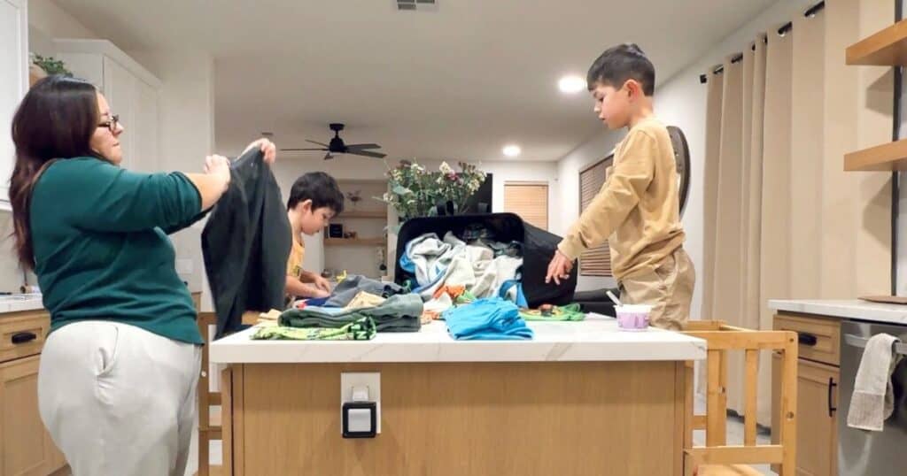 a mom (myself) wearing a green shirt folding laundry with 2 boys in the kitchen
