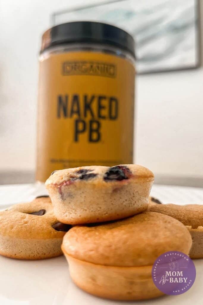 Close up image of the mini pancake muffins on a white plate, in front of the powdered peanut butter tub.