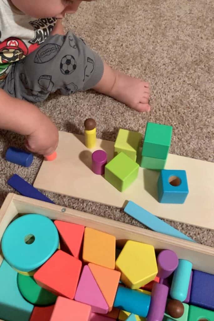 A close up image of a young toddler playing with the Lovevery Block Set