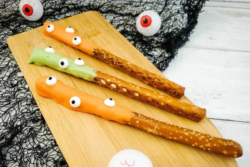 This image shows chocolate dipped pretzels in a halloween theme with candy eyeballs on them 