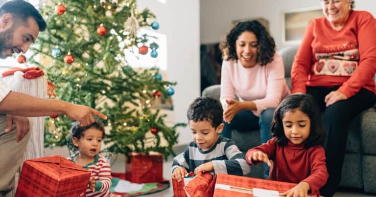 the image shows a happy family opening gifts next to a christmas tree. The image is a cover image for the article: enchanting family christmas quotes