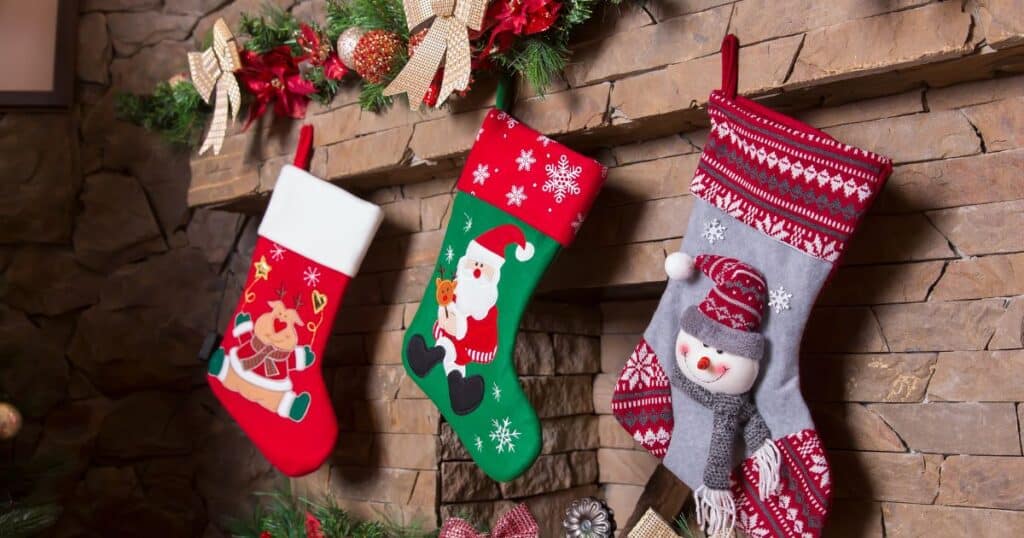festive stockings in red, green, and white hanging on a brown mantle