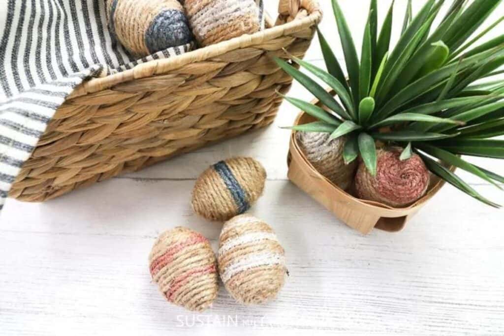 flatlay image of twine wrapped easter egg craft next to faux table plant in clean and simple aesthetic background. Made by Sustain my craft habit