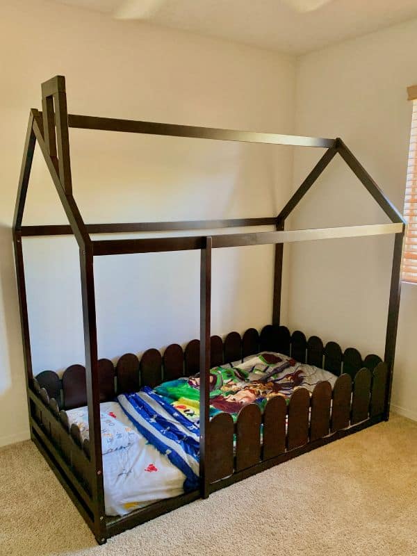 image of a kid's floor bed that's shaped like a house with a toy story blanket on top