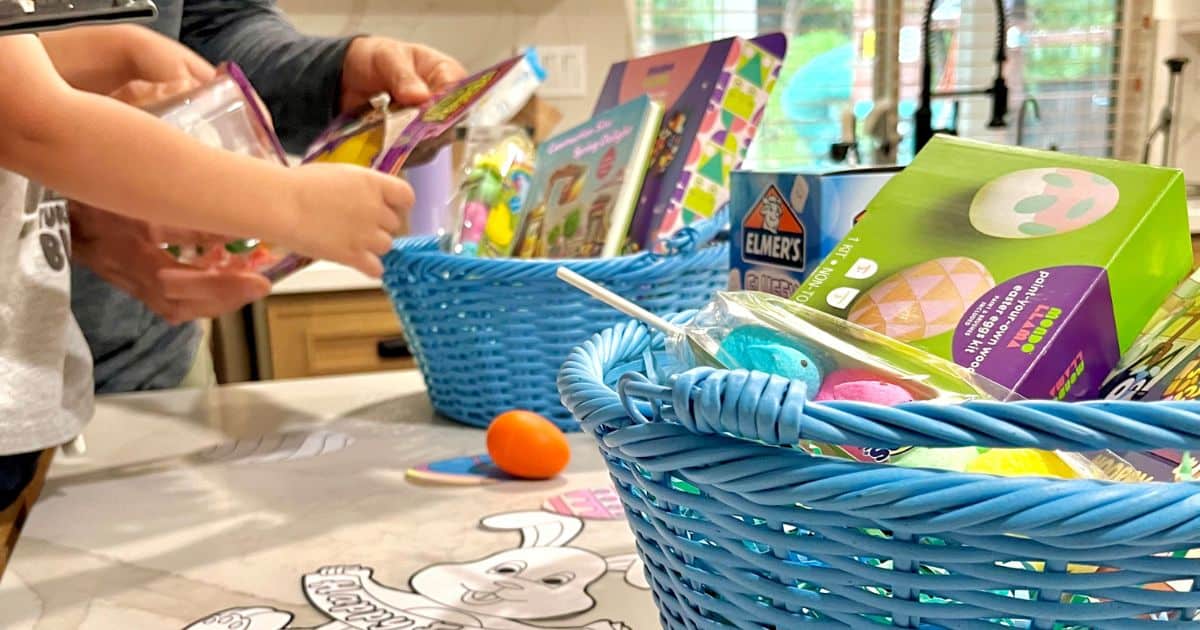 close up of blue easter baskets on a white marble counter filled with shredded paper, crafts, peeps, and other goodies