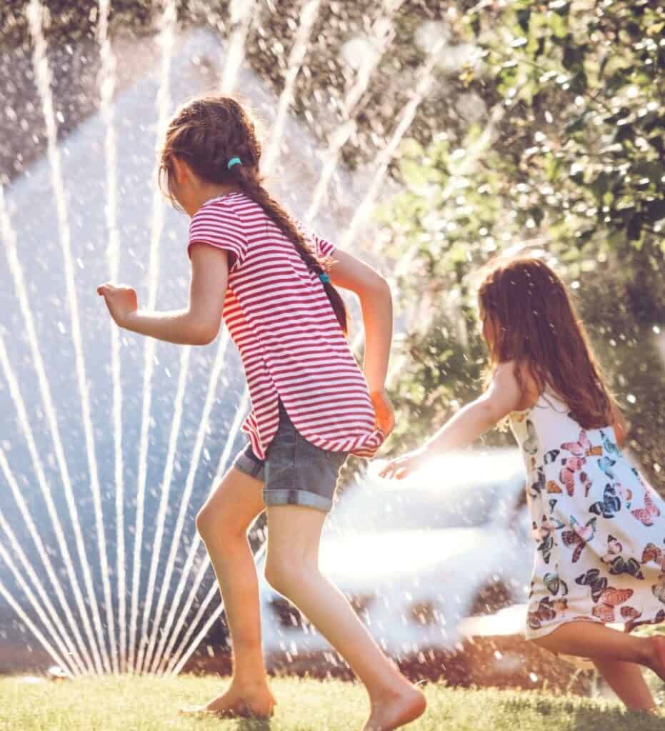 close up image of kids playing in a sprinkler