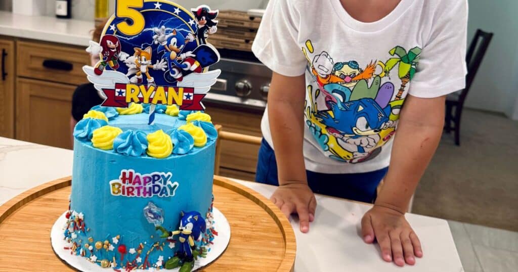 Image of a sonic the hedgehog cake next to a child for a sonic the hedgehog birthday party