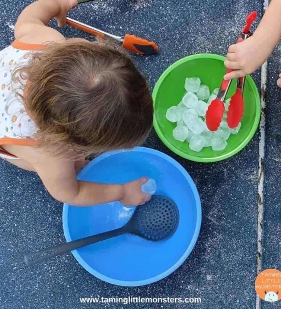 flatlay image of a child playing with ice and tongs/grabbers