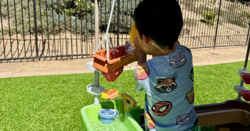 cover image of a little boy playing and pouring water on a water table