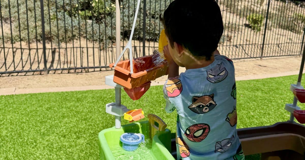 cover image of a little boy playing and pouring water on a water table