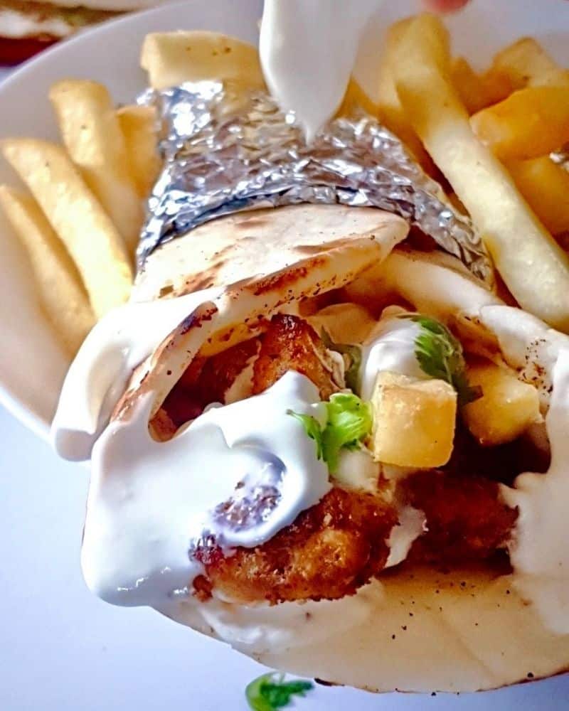 Chicken shawarma wrap on a plate with french fries