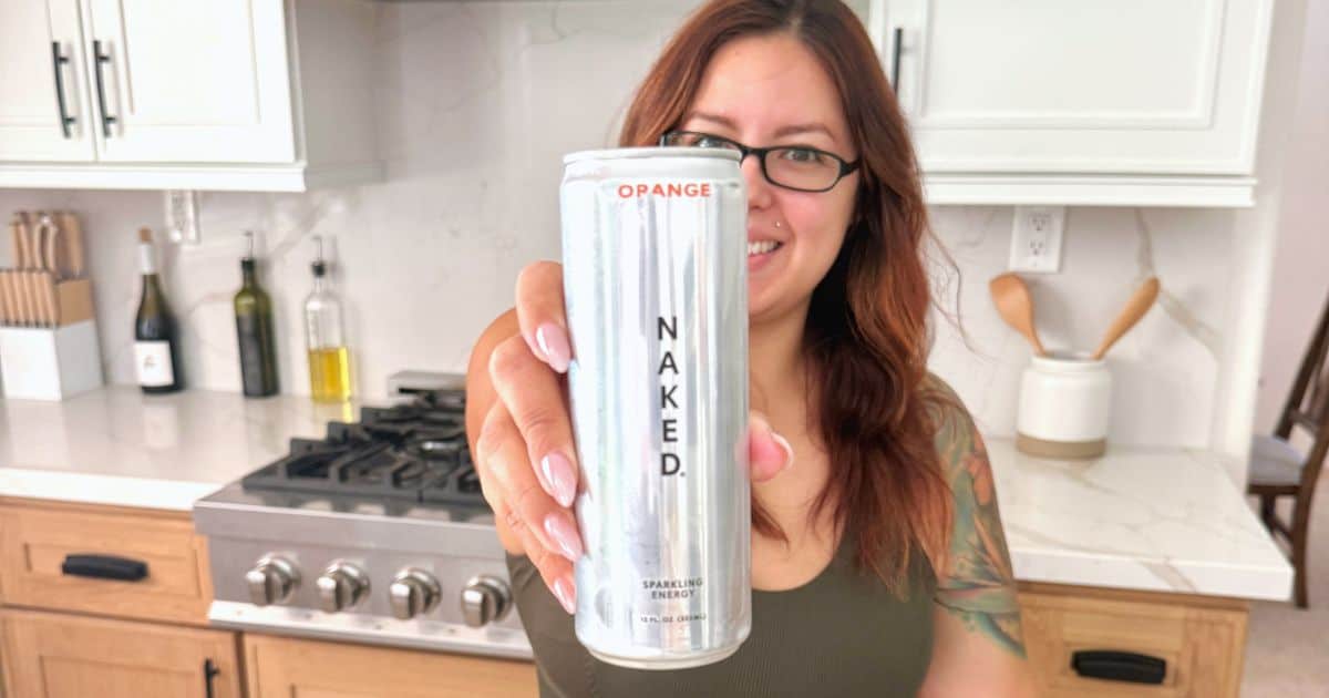 woman holding up a Naked Nutrition Energy drink can in the kitchen