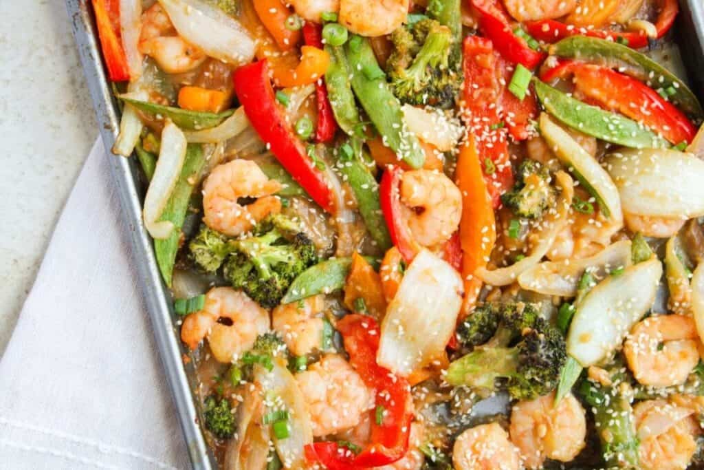 Close up image of shrimp and vegetable stir fry on a baking pan