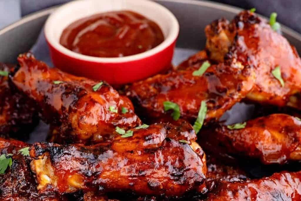 Close up image of some air fryer bbq chicken wings next so sauce.