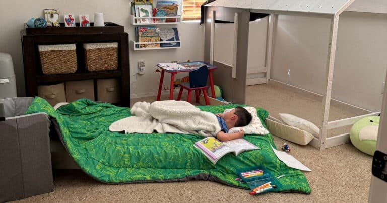young child sleeping on a mattress on the floor in their room
