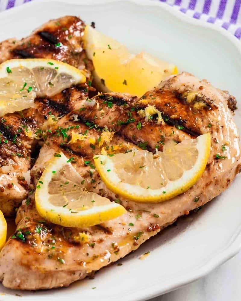 Grilled Lemon Chicken on a plate with Lemon Slices and seasoning