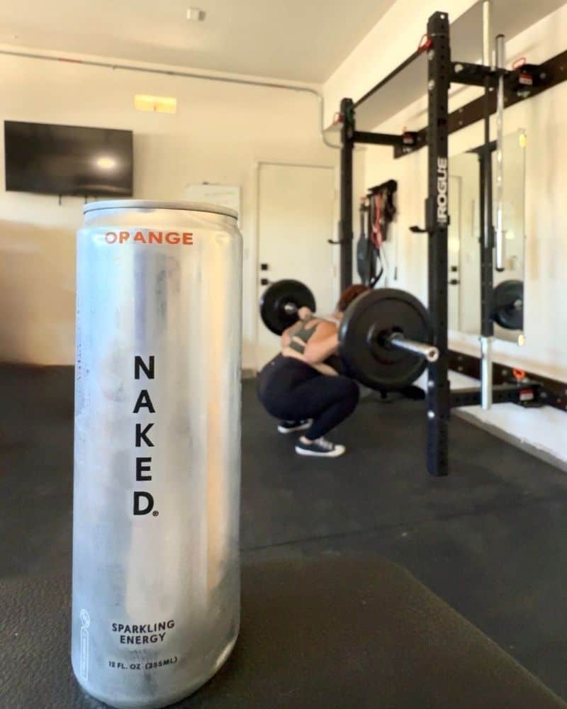close up image of Naked Nutrition Energy Drink can with girl working out in the background