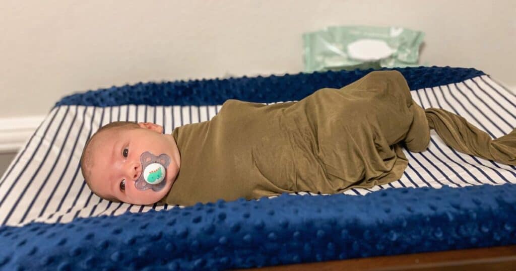 close up image of a newborn baby in a swaddle on a changing table