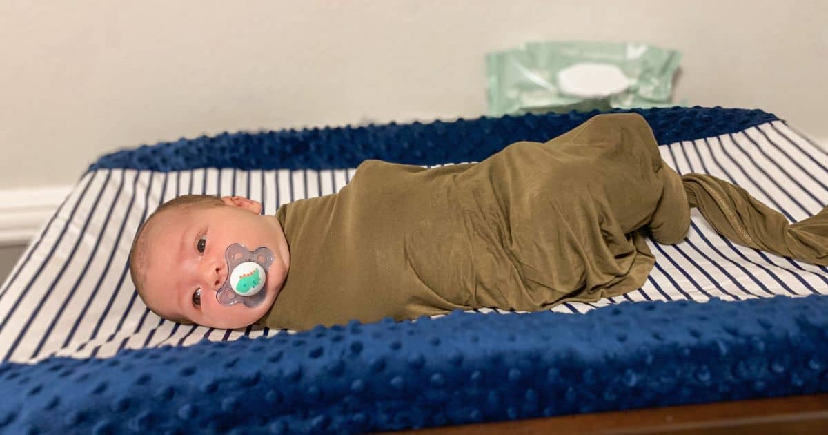 close up image of a newborn baby in a swaddle on a changing table
