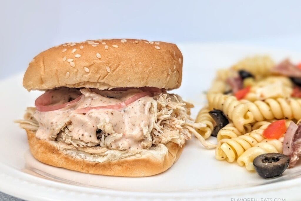 Close up of plated Chicken Sandwich next to pasta salad