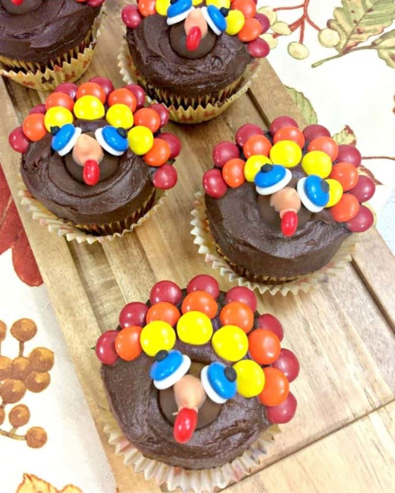 chocolate cupcakes decorated to look like a turkey using m&ms, and candy eyes