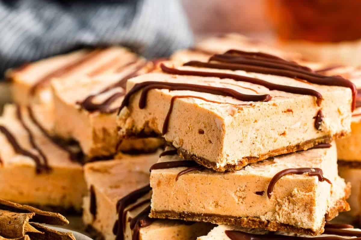 close up pumpkin cheesecake bars drizzled with chocolate