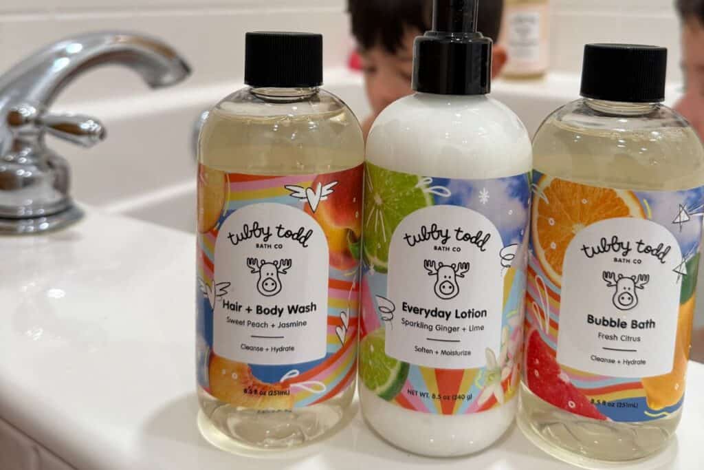 Image of 3 Tubby Todd bottles of bath wash and body lotion on the edge of a bathtub