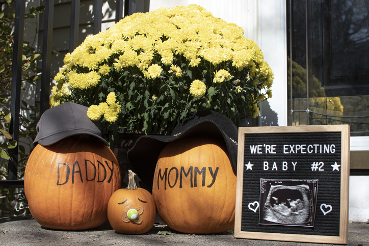 Mommy, daddy, and baby pumpkin baby announcement photo.