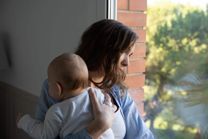mom holding baby while looking out the window